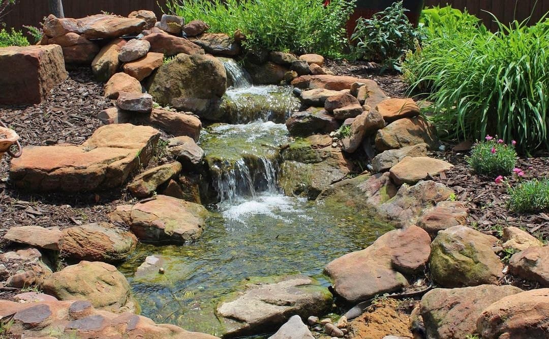 Stone water feature built into a planted bed