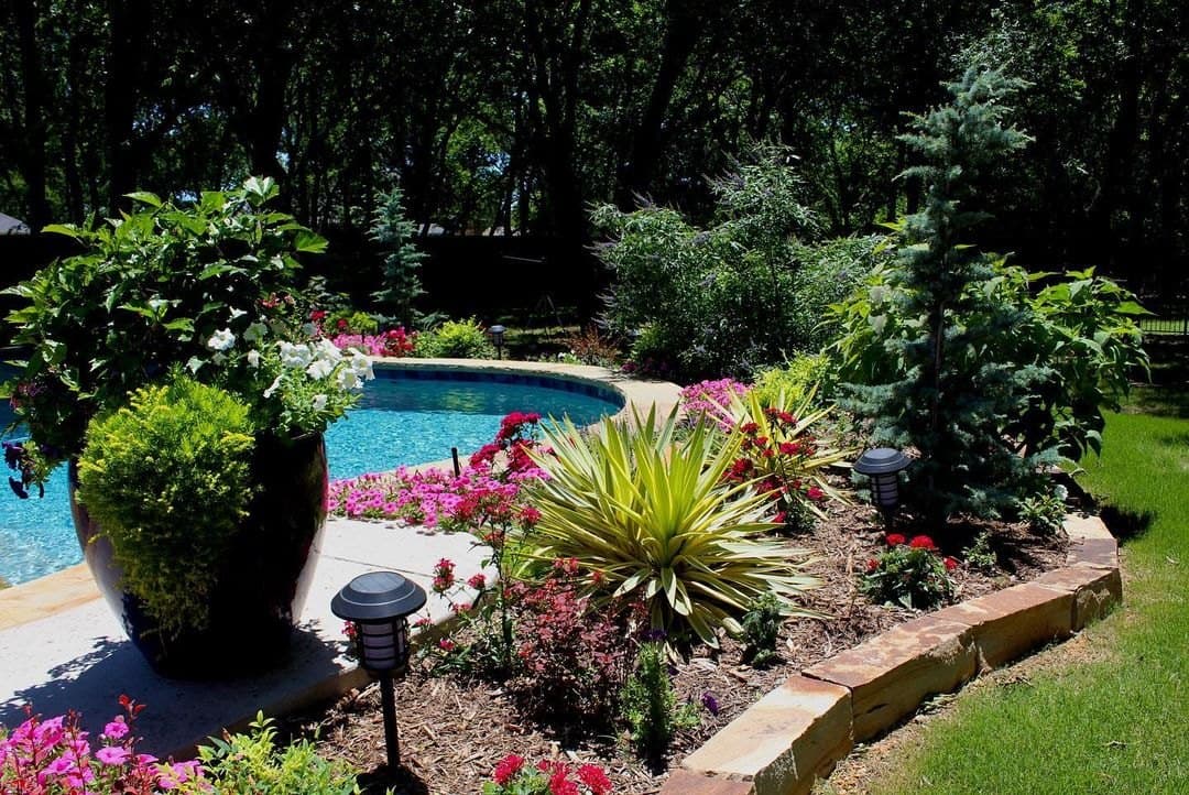 Seasonal flowers planted in a bed beside a pool deck