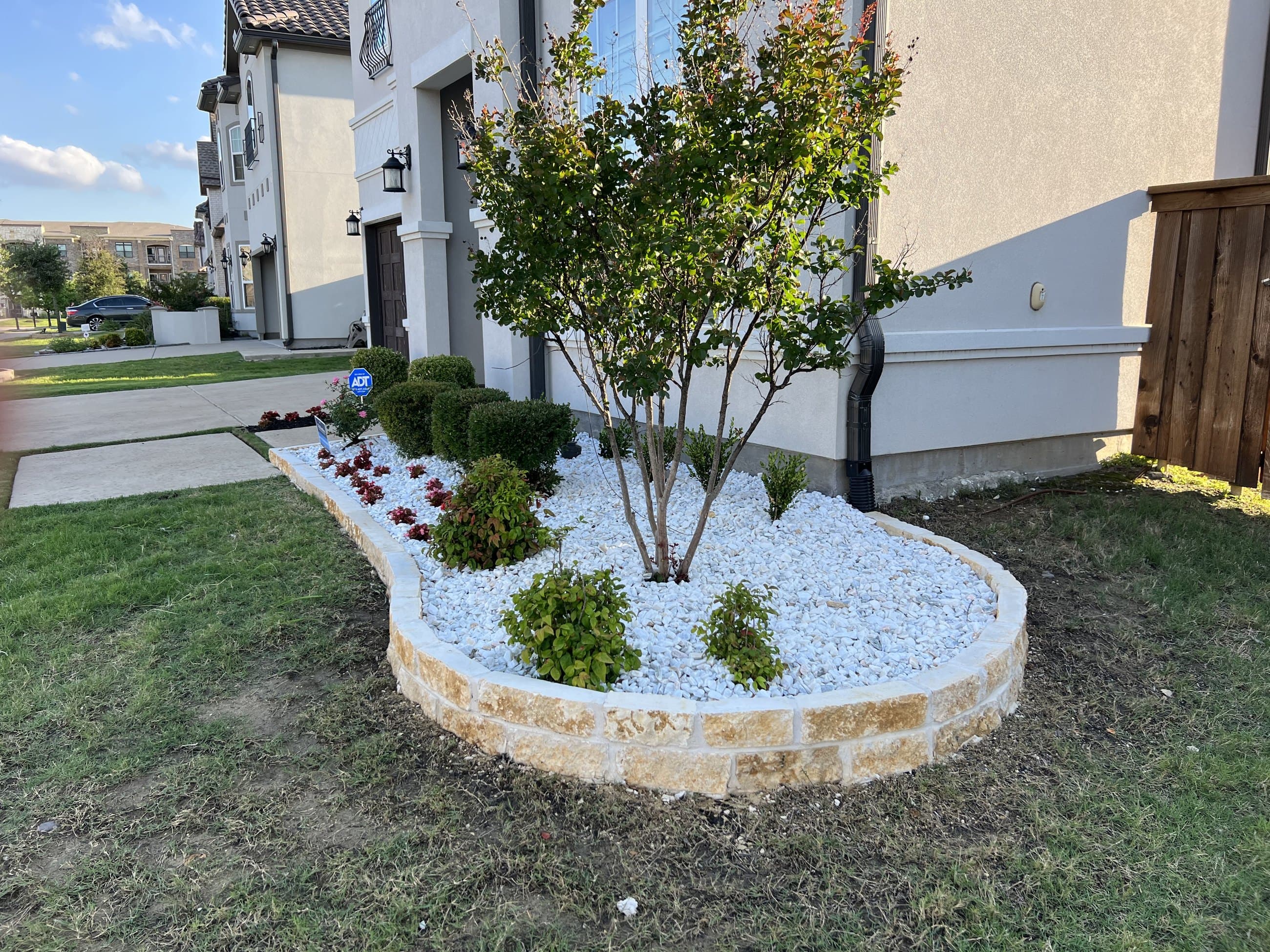 White rock bed with drought-tolerant planting along a home
